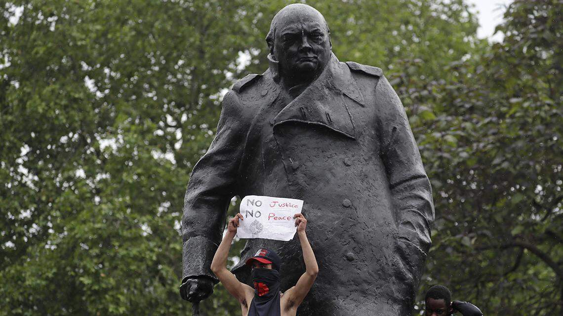 Protesters stand on the statue of former British Prime Minister Winston Churchill during a demonstration in Parliament Square in London on Wednesday, June 3, 2020, over the death of George Floyd, a black man who died after being restrained by Minneapolis police officers on May 25.