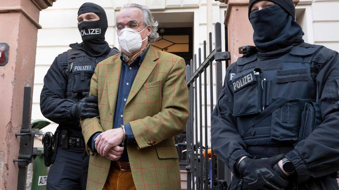 Masked police officers lead Heinrich XIII Prince Reuss, center, to a police vehicle during a raid against so-called ‘Reich citizens’ in Frankfurt, Germany, Wednesday, Dec. 7, 2022.