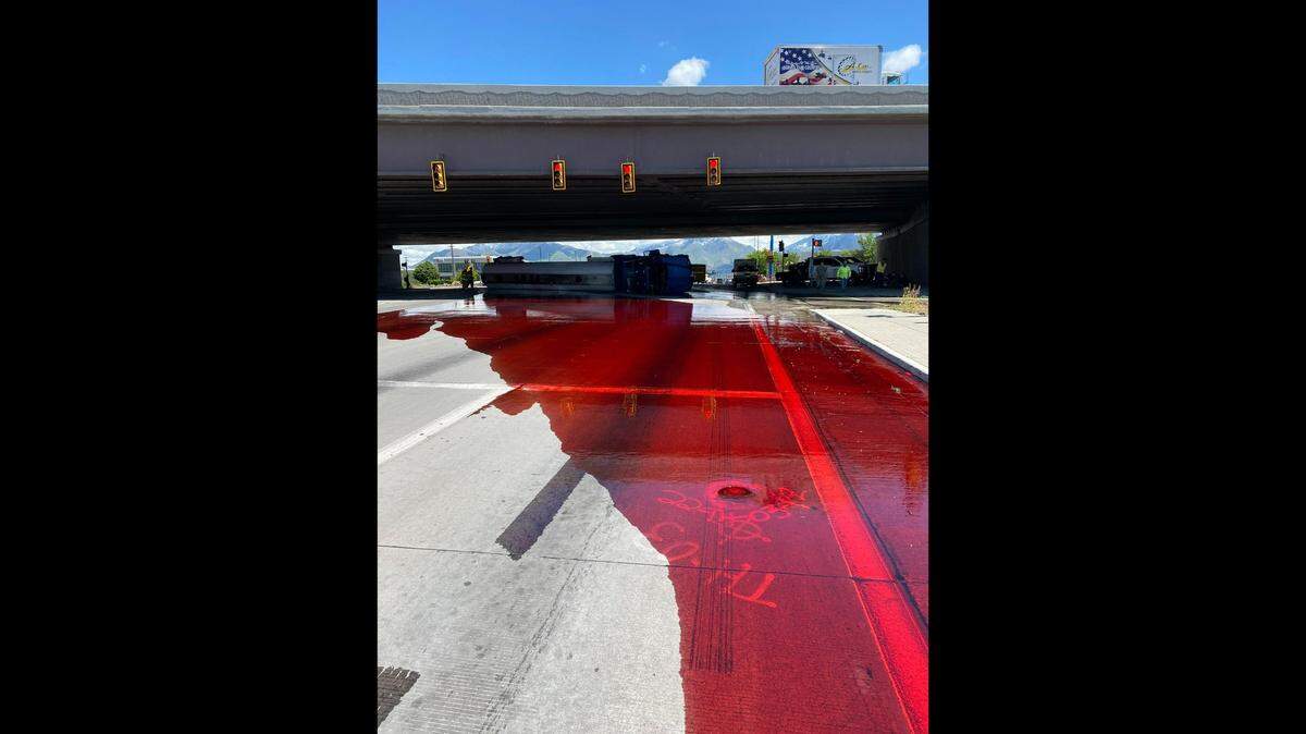 An unknown red liquid spread onto a Utah highway after a rollover semitruck crash.