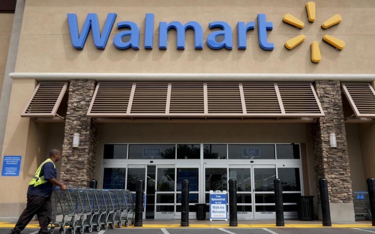 FILE - In this May 9, 2013, file photo, a worker pushes shopping carts in front of a Walmart store in La Habra, Calif. By next month, the company hopes to reduce wait times to 30 seconds for some kind of in-store returns.