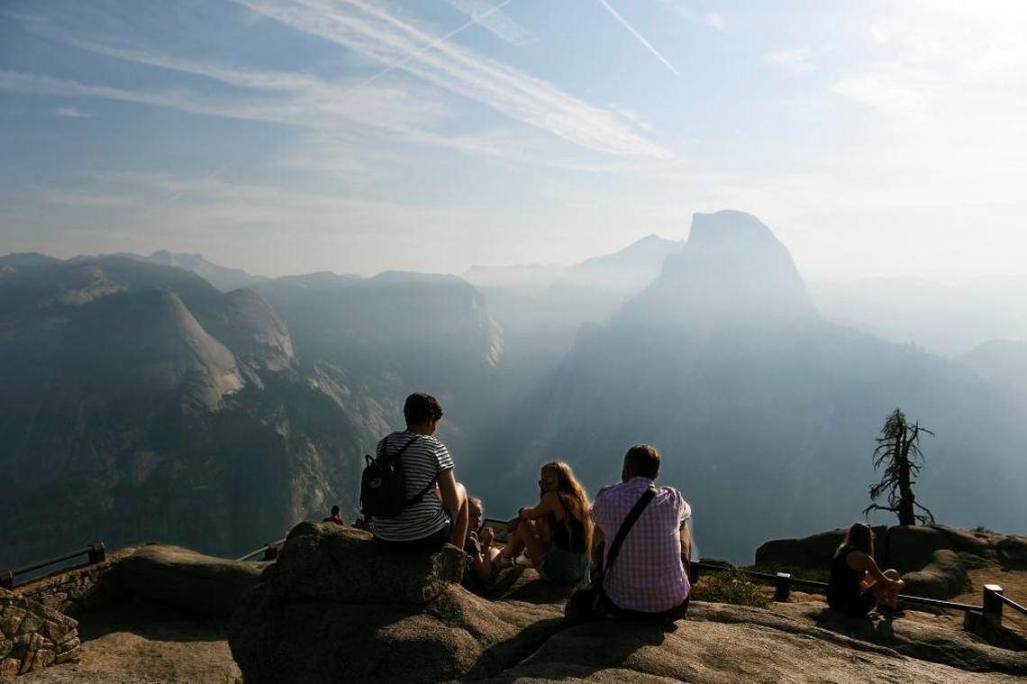 Visitors enjoy a hazy view of Half Dome from Glacier Point at Yosemite National Park Yosemite on Thursday, Aug. 3, 2017.