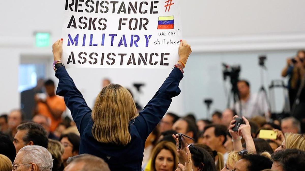 Woman holds up a sign as Vice President Mike Pence gives his remarks after meeting with several political exiles to highlight the Venezuelan crisis at Our Lady of Guadalupe Catholic Church, in Doral, Fla., on Wednesday, Aug. 23, 2017.