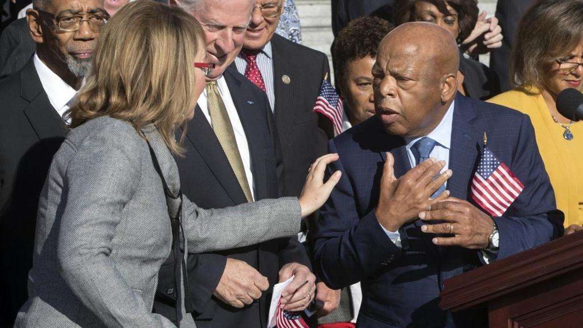 Former Rep. Gabby Giffords, D-Ariz., who survived an assassination attempt in 2011, left, reaches out to civil rights leader Rep. John Lewis, D-Ga., right, as House Democrats call for action on gun safety legislation after the deadly mass shooting in Las Vegas, at the Capitol in Washington, Wednesday, Oct. 4, 2017.