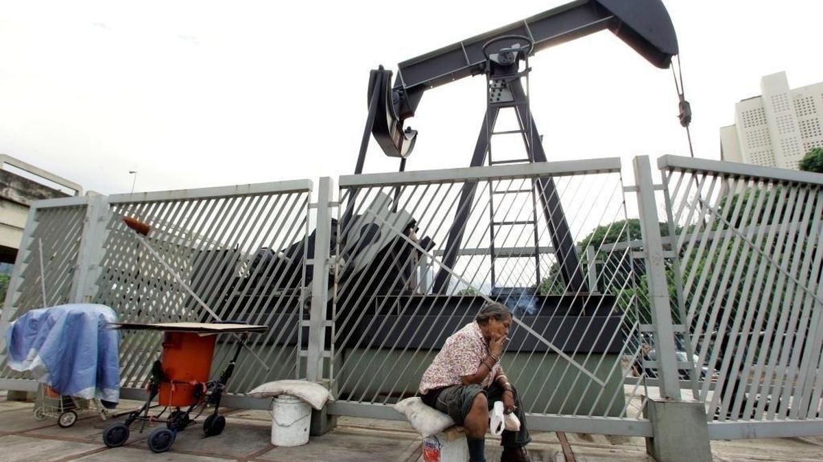 Homeless woman Carmen Elena Sanchez smokes a cigarette under a sculpture of an oil drill in Caracas, Venezuela on May 31, 2006