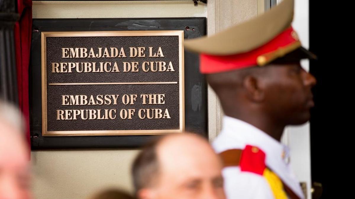 A member of the Cuban honor guard stands next to a new plaque at the front door of the newly reopened Cuban embassy in Washington in this July 20, 2015. The State Department has expelled two diplomats from Cuba’s Embassy in Washington following a series of unexplained incidents in Cuba that left U.S. officials there with physical symptoms.