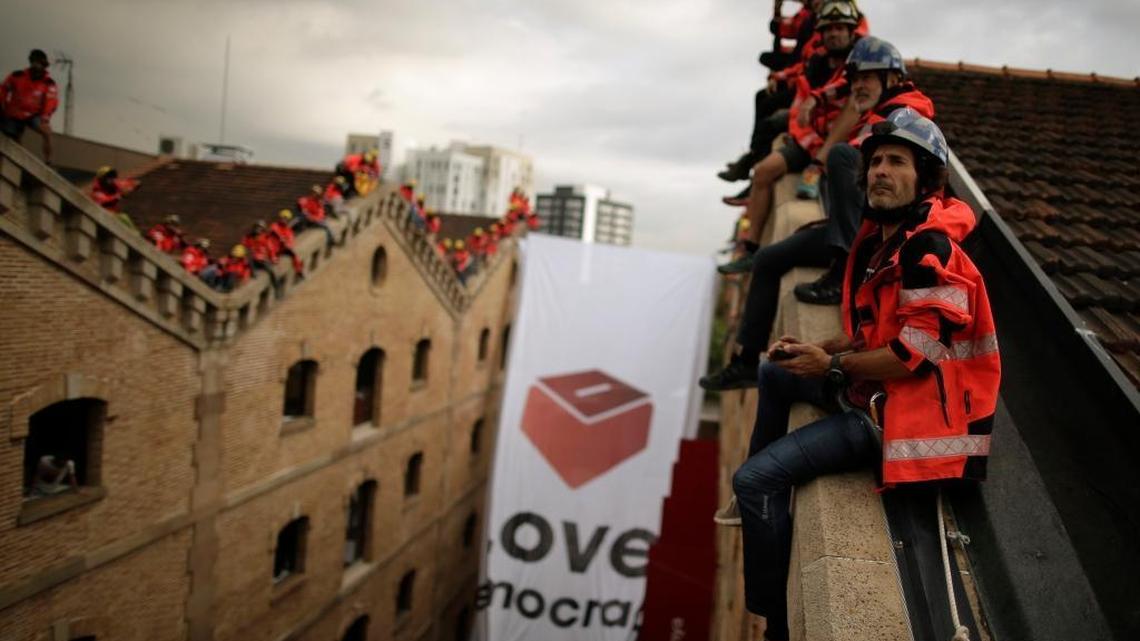 Catalan firefighters unfold a large banner with a ballot box at the Museum of History of Catalonia in Barcelona, Spain, Thursday, Sept. 28, 2017. Banner reads: "Love Democracy."