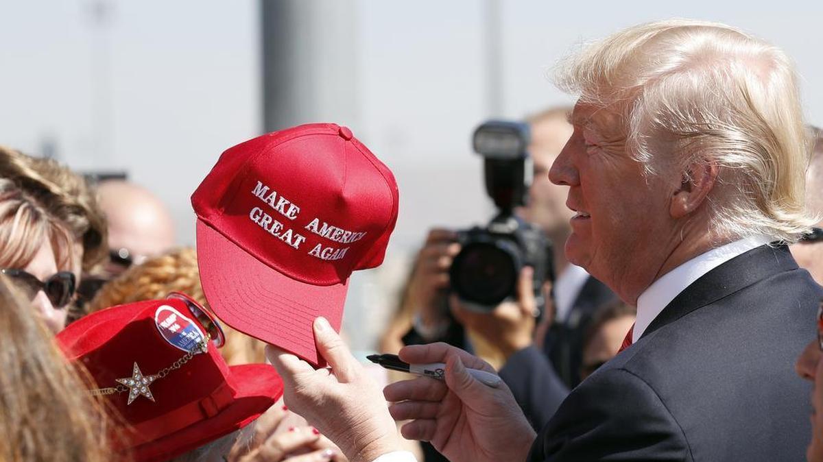 President Donald Trump hands a signed "Make America Great Again," hat back to a supporter. The iconic hat has become the center of a law suit in New York.