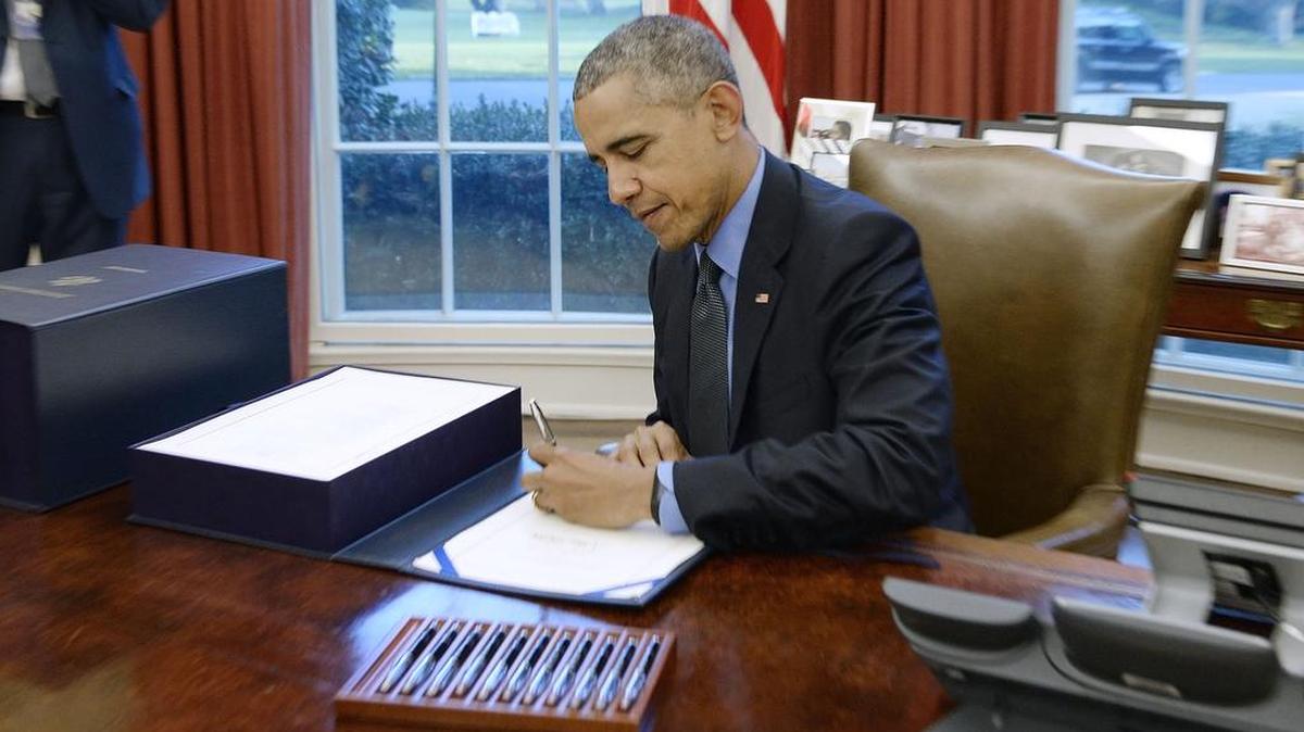 US President Barack Obama signs a compromise $1.1 trillion spending package that funds the government through next September in the Oval Office at the White House on Dec. 18, 2015 in Washington, D.C.