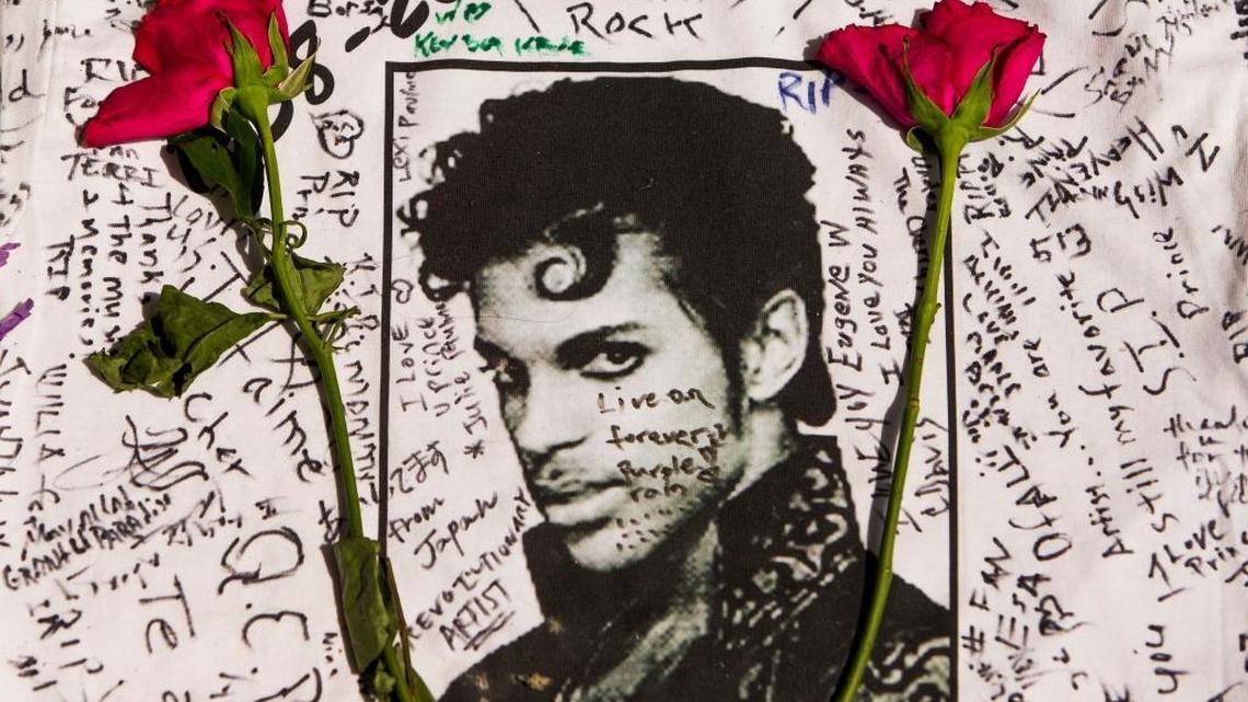 Flowers lay on a T-shirt signed by fans of the musician Prince at a makeshift memorial created outside the Apollo Theatre in New York on Friday, April 22, 2016. The pop star died Thursday at age 57.