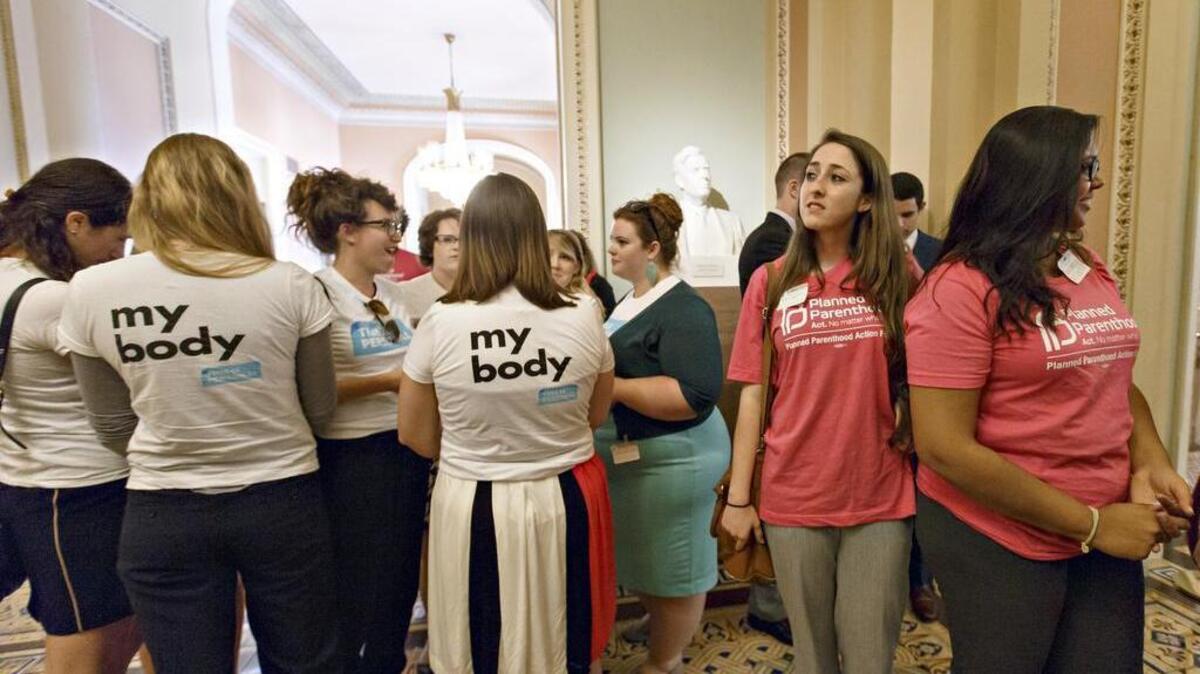 Women activists representing the National Women's Law Center, left, and Planned Parenthood, right, stand outside the Senate chamber after Senate Democrats' effort to proceed on the “Protect Women’s Health From Corporate Interference Act,” was thwarted, on Capitol Hill in Washington, Wednesday, July 16, 2014.