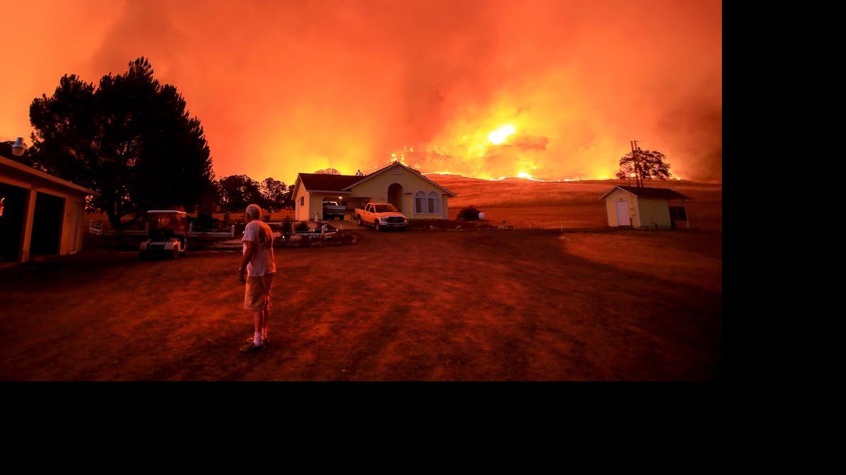 
A wall of flames lurches over a ridge as a resident of Morgan Valley Road near Lower Lake, Calif., prepares to evacuate because of the Rock Fire, Wednesday evening July 29, 2015.
