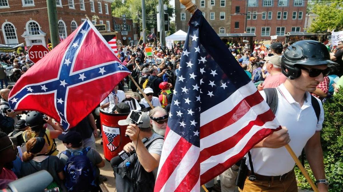 White nationalist demonstrators walk into Lee park surrounded by counter demonstrators in Charlottesville, Va., Saturday, Aug. 12, 2017. Gov. Terry McAuliffe declared a state of emergency and police dressed in riot gear ordered people to disperse after chaotic violent clashes between white nationalists and counter protestors.