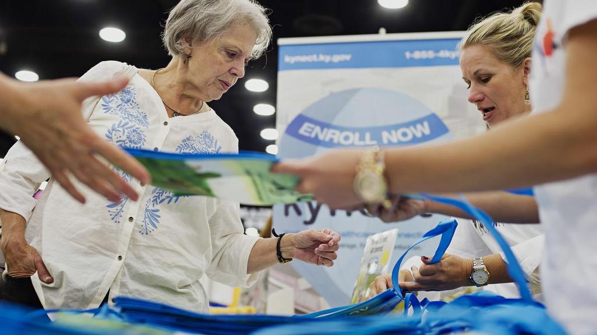 Jean Varble, 65, left, stops by an information booth run by Kynect, the state’s health insurance marketplace, at the Kentucky State Fair in Louisville, Ky. in 2014. Kentucky led the eight states that saw a significant drop last year in the number of residents going without health insurance, according to a government report out Tuesday.