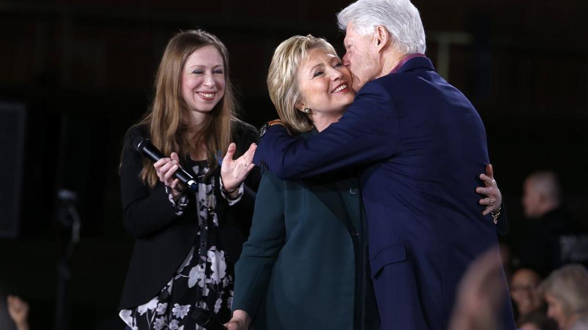 Democratic Presidential candidate Hillary Clinton gets a kiss from her husband and former President Bill Clinton as daughter Chelsea looks on during a rally at the Clark County Government Center on Friday, Feb. 19, 2016.
