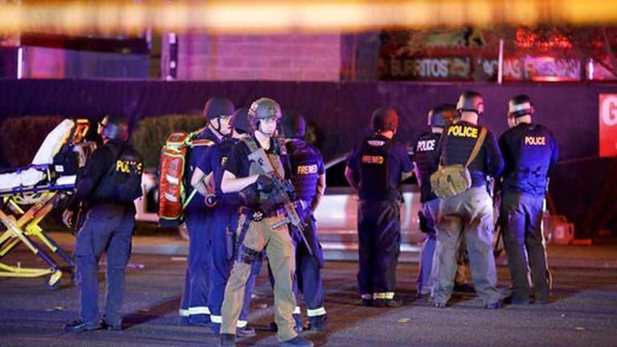 Police officers and medical personnel stand at the scene of a shooting near the Mandalay Bay resort and casino on the Las Vegas Strip, Monday, Oct. 2, 2017, in Las Vegas. Multiple victims were being transported to hospitals after a shooting late Sunday at a music festival on the Las Vegas Strip.
