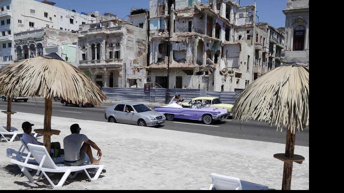 
People sit on deck chairs on an artificial beach as a bride and groom ride by in a convertible on the Malecon in Havana, Cuba, Thursday. With efforts to lift the Cuban embargo stalled in Congress, a pro-trade senator from Kansas is trying to break the stalemate by offering new legislation.
