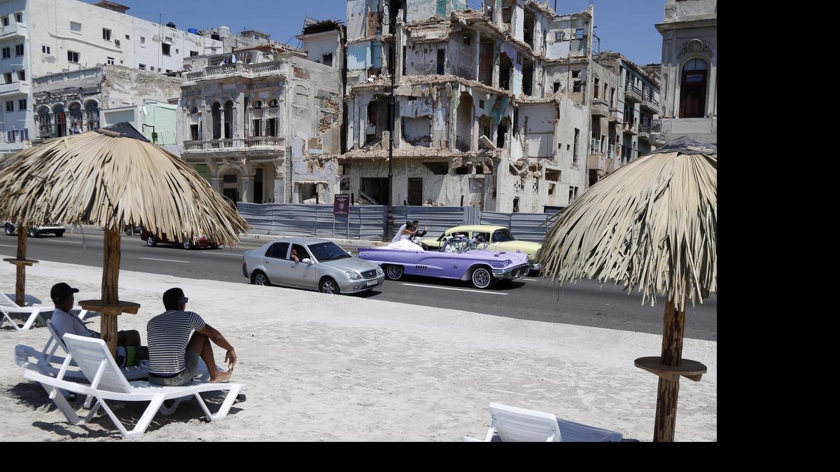 
People sit on deck chairs on an artificial beach as a bride and groom ride by in a convertible on the Malecon in Havana, Cuba, Thursday. With efforts to lift the Cuban embargo stalled in Congress, a pro-trade senator from Kansas is trying to break the stalemate by offering new legislation.
