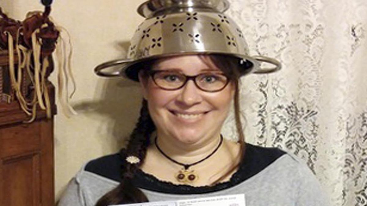 In this Nov. 12, 2015 photo provided by Darrick Fauvel, Lindsay Miller of Lowell, Mass., wears a spaghetti strainer to reflect her religious beliefs while holding her temporary driver license that also bears a photo of her wearing the colander. Miller said she “absolutely loves the history and the story” of Pastafarians, who are part of the Church of the Flying Spaghetti Monster. The Massachusetts Registry of Motor Vehicles initially forbade Miller to wear the colander in the identification photo. She said the agency reversed the decision and apologized.