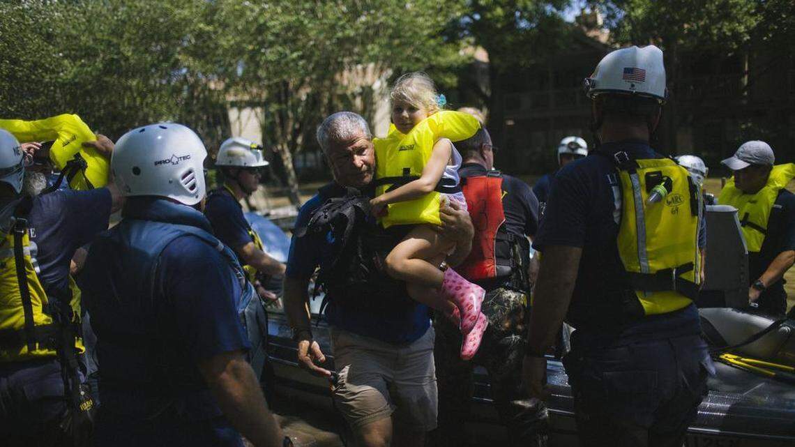 Ken Jacobs carries 5-year-old Astrid Galperin from a rescue boat on Thursday. Jacobs, who is operations director for a kayak tour/rental business in Houston, was one of many everyday residents who played a role in rescue efforts.