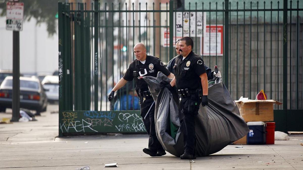 Los Angeles police remove the belongings of a person detained on outstanding warrants downtown. The City Council voted to approve revisions to a hotly debated ordinance approved last fall aimed at sweeping homeless people's belongings from city streets.
