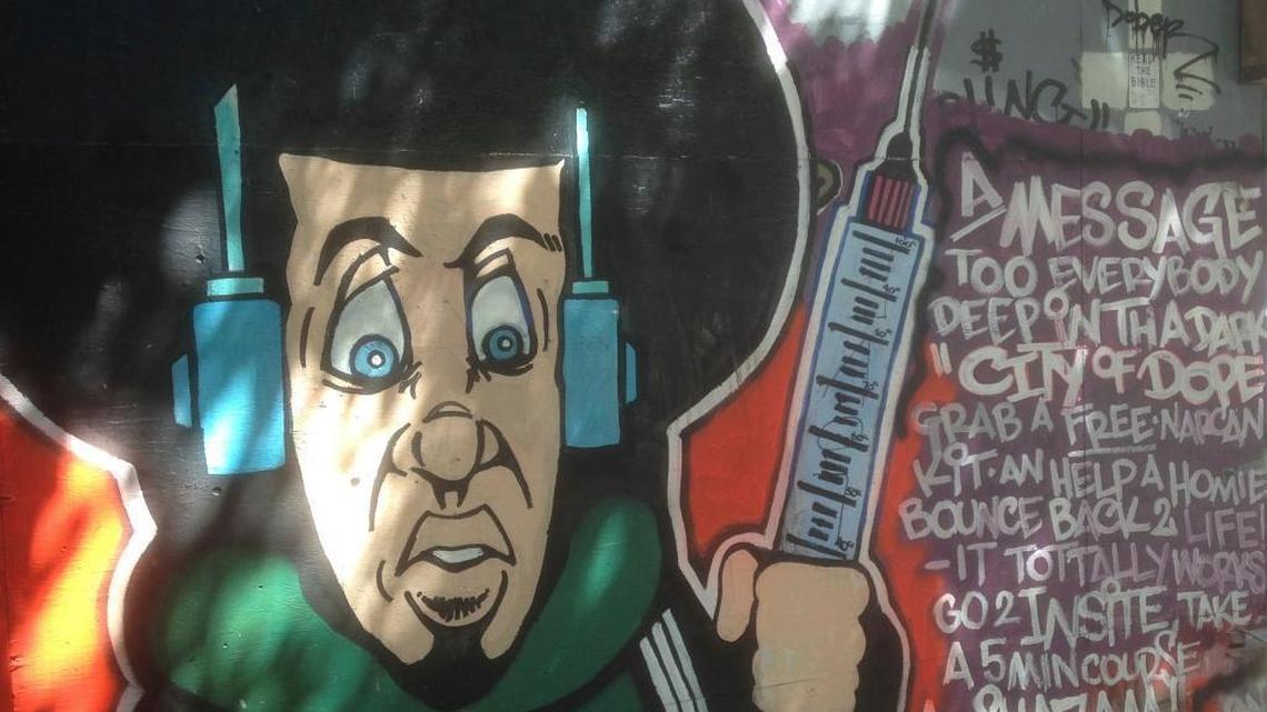 In this June 28, 2017 photo, a mural encourages people to pick up the overdose antidote Narcan at a nearby "safe injection site" on the east side of downtown Vancouver, Canada. A single safe injection site opened in 2003, run by a Vancouver nonprofit organization under authorization by Health Canada, and says it's never had an overdose death.