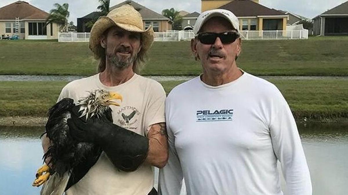 Justin Matthews and David Anderson pose for a photo with the eagle that Anderson rescued from the jaws of an alligator Wednesday. The eagle had to be euthanized.