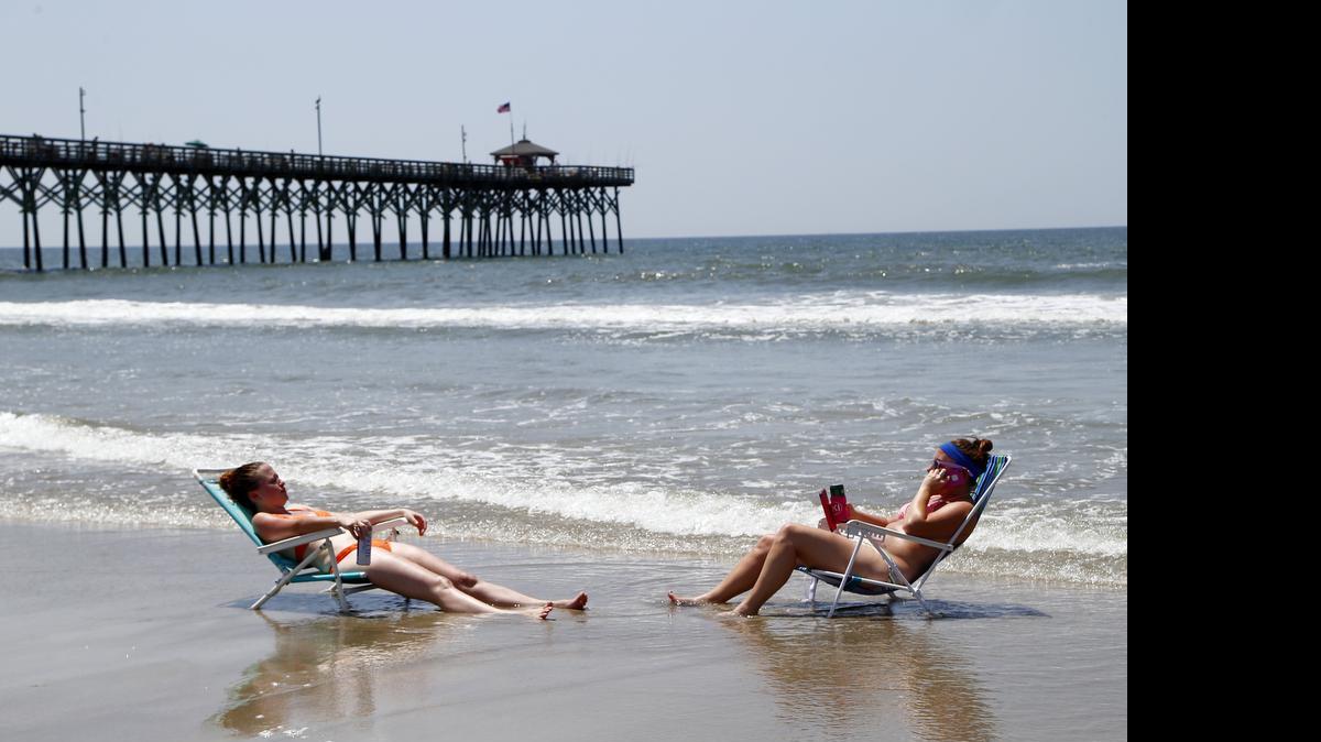 
Friends Jessica Bresnan, left, from Greenville PA and Katie Simunich from Louisa VA relax in the surf on Oak Island beach near the Ocean Crest Pier as life resumes here on Monday, June 15, 2015. On Sunday, two people were attacked by sharks while swimming in this southeastern North Carolina town. One of the attacks several hundreds yards from here on the other side of the pier. On Monday, a few people went into the water, but not very far out. Most were either on the sand or just in the surf where the water was only a foot or two deep.
