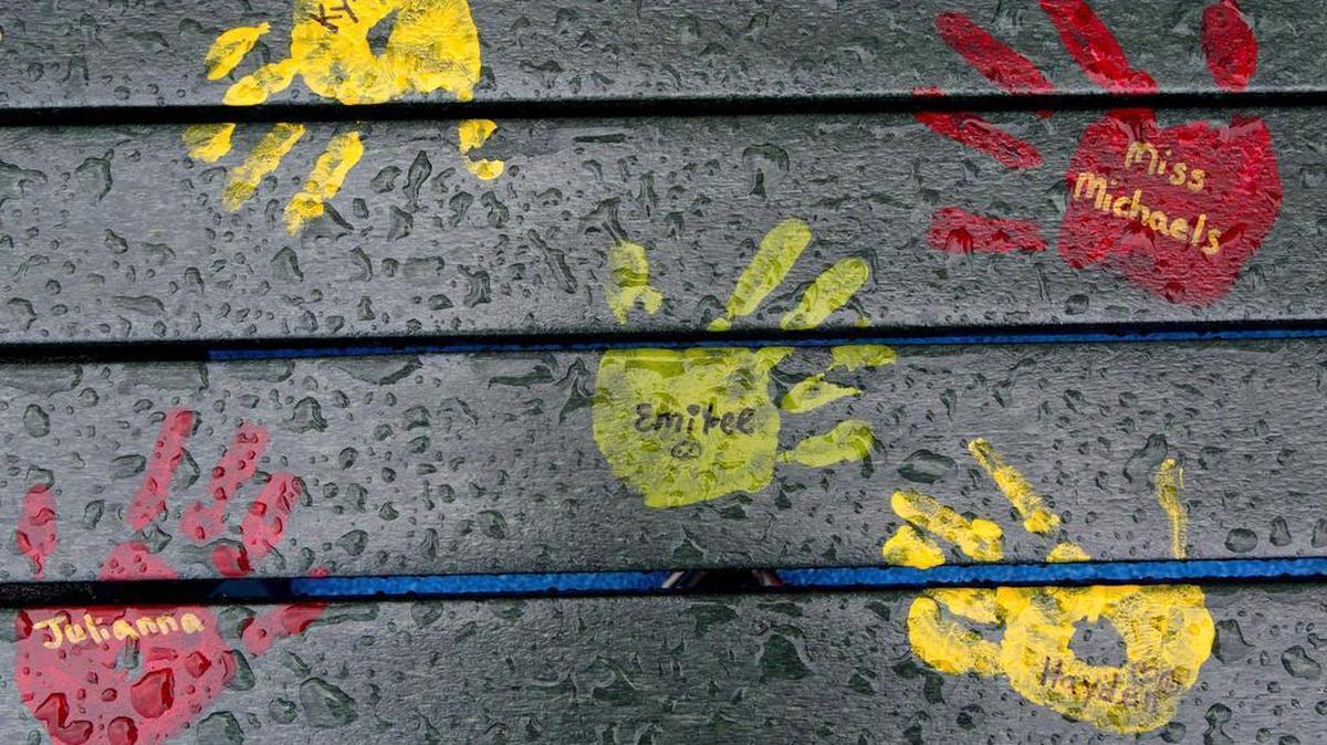 FILE - In this July 29, 2016 file photo, painted hand prints with names of teachers and students are on a playground bench at the new Sandy Hook Elementary School in Newtown, Conn. Students attended the first day of classes there on Monday, Aug. 29, 2016. The new building replaced the one that was demolished where 20 first graders and six educators were shot and killed in December 2012. The names on the bench are not those of people killed in the 2012 massacre at the school.