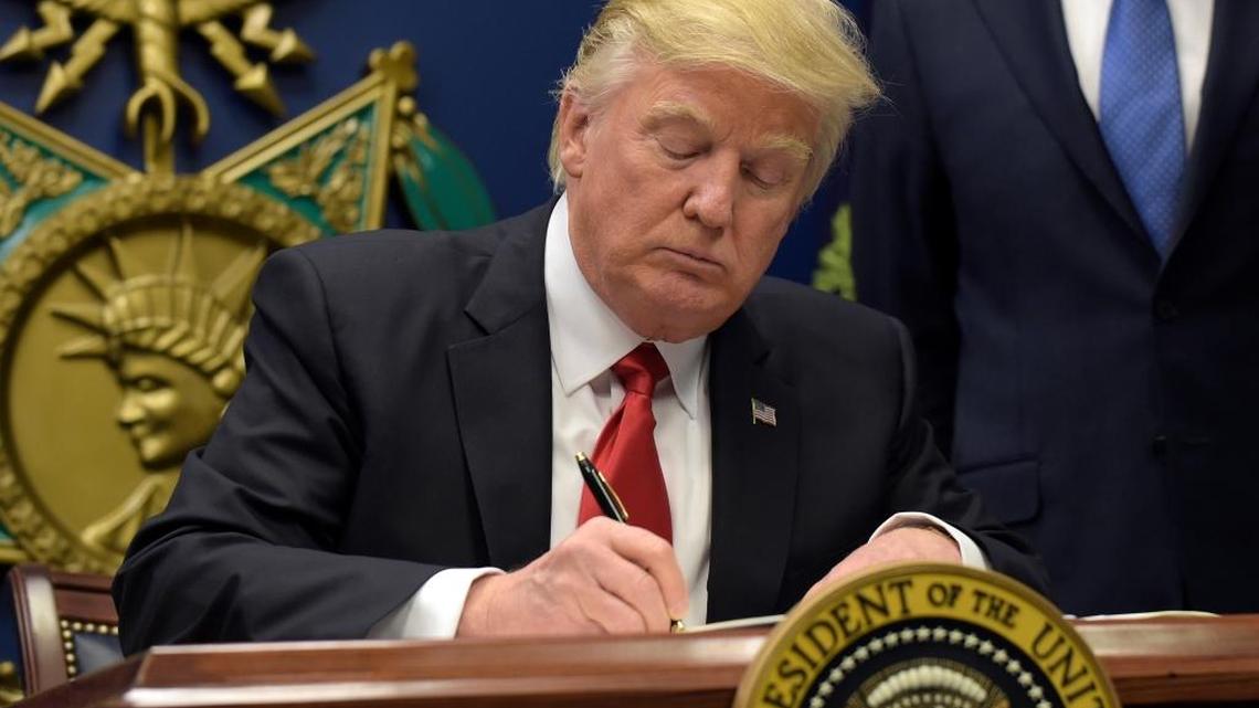 President Donald Trump signs an executive order blocking Syrians from being granted refugee status and limiting immigration from seven Muslims-majority countries for 90 days.