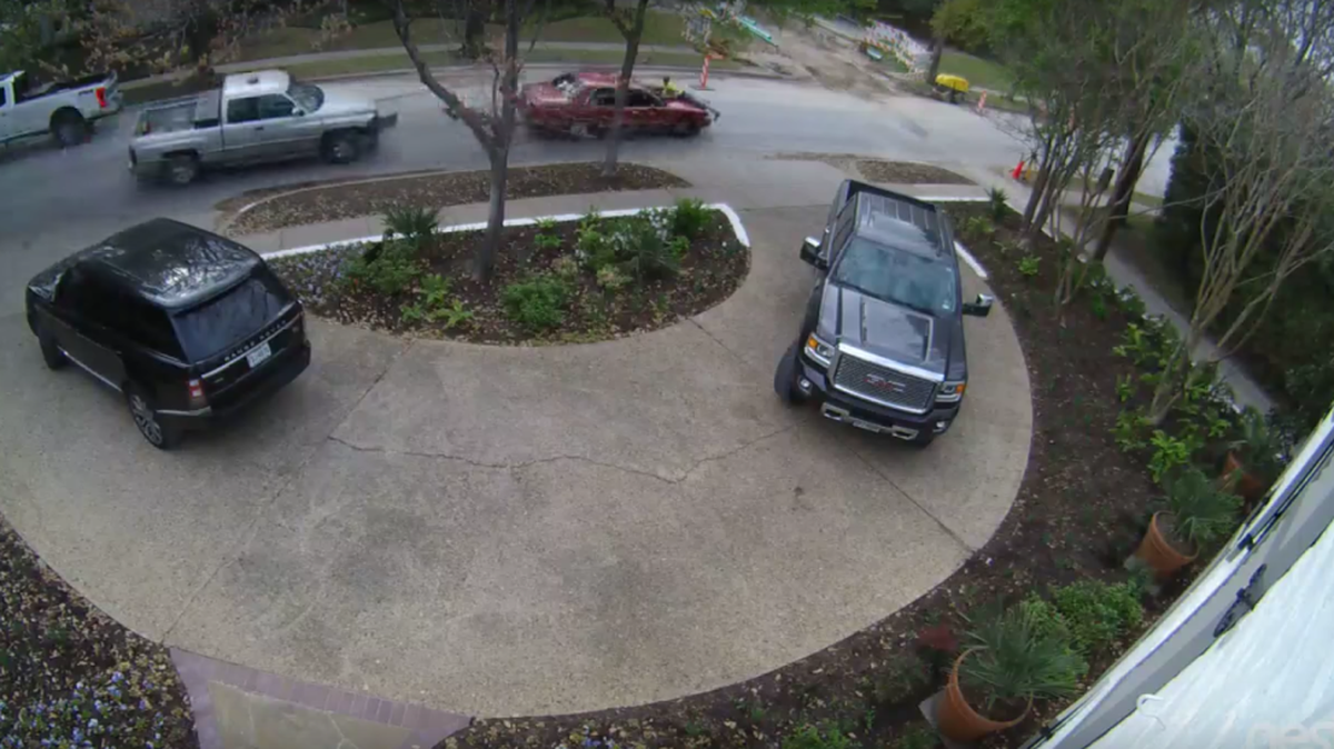 One of the construction workers clings to the hood of the thief’s car while another pursues him in a pickup truck.