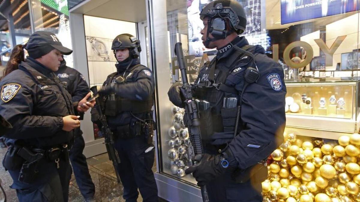 Counterterrorism officers stand in front of a watch store in Times Square, Thursday, Dec. 29, 2016, in New York, as they take shelter from the rain. Police say they are ready for the job of protecting the huge crowds that are expected to gather in Times Square for New York City's massive New Year's Eve celebration. They have the additional task of protecting people against truck attacks like the ones recently in Berlin and earlier this year in Nice.