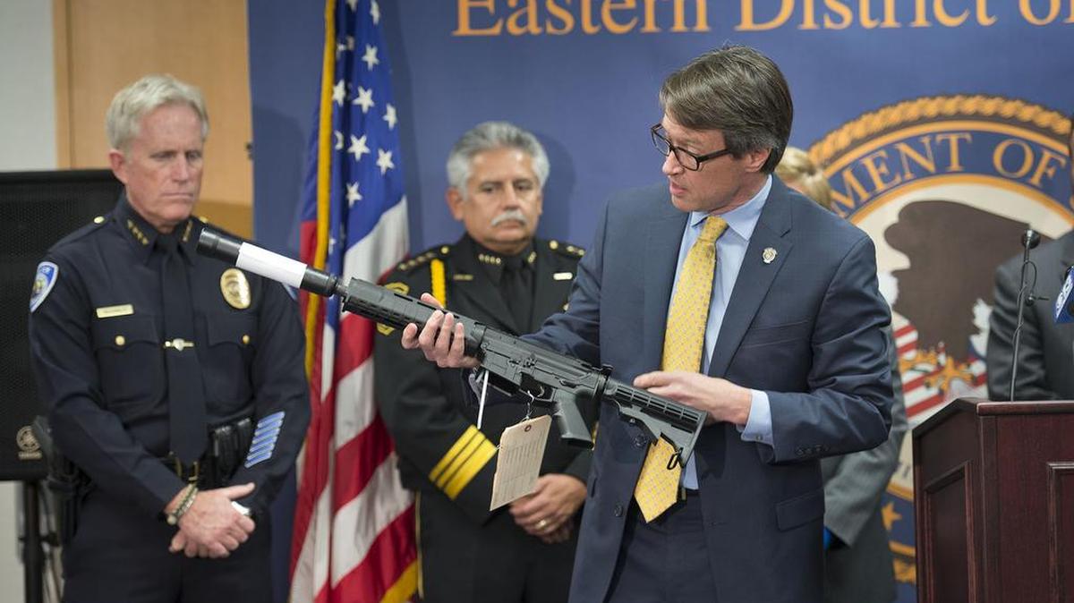 U.S. Attorney Benjamin Wagner holds an AR-15 type assault weapon Thursday in Sacramento as he describes the indictment of eight suspects. Several of the high-capacity assault rifles were sold to undercover agents.
