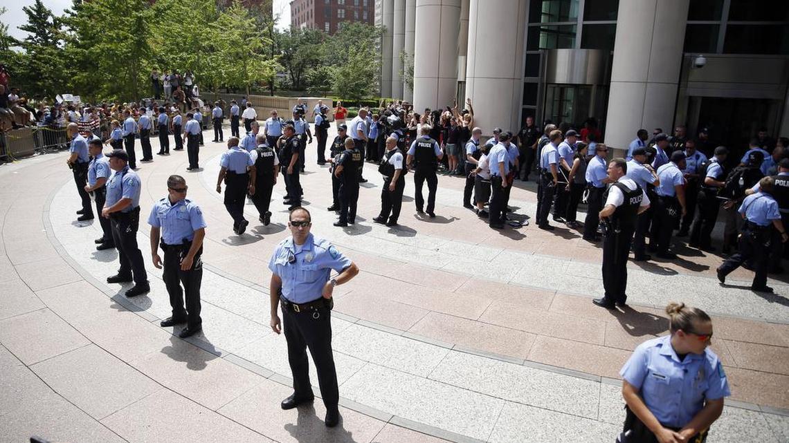 
Members of the St. Louis police department form a line outside the Thomas F. Eagleton Federal Courthouse as protesters are arrested in the background Monday, Aug. 10, 2015, in St. Louis. Protesters have been arrested after blocking the entrance to the St. Louis federal courthouse while calling for more aggressive U.S. government response to what they call racist law enforcement practices.
