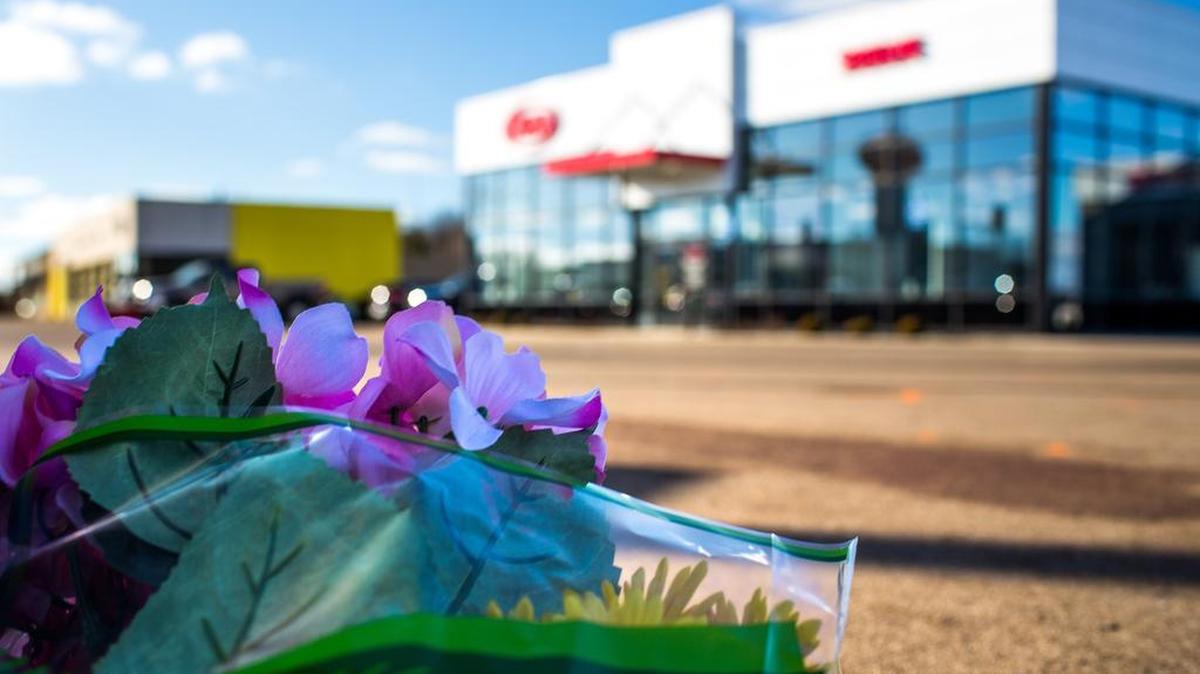 Flowers rest in the parking lot of a car dealership, Sunday, Feb. 21, 2016, in Kalamazoo, Mich. According to police a man drove around Kalamazoo fatally shooting several people at multiple locations on Saturday. Authorities identified the shooter as Jason Dalton.