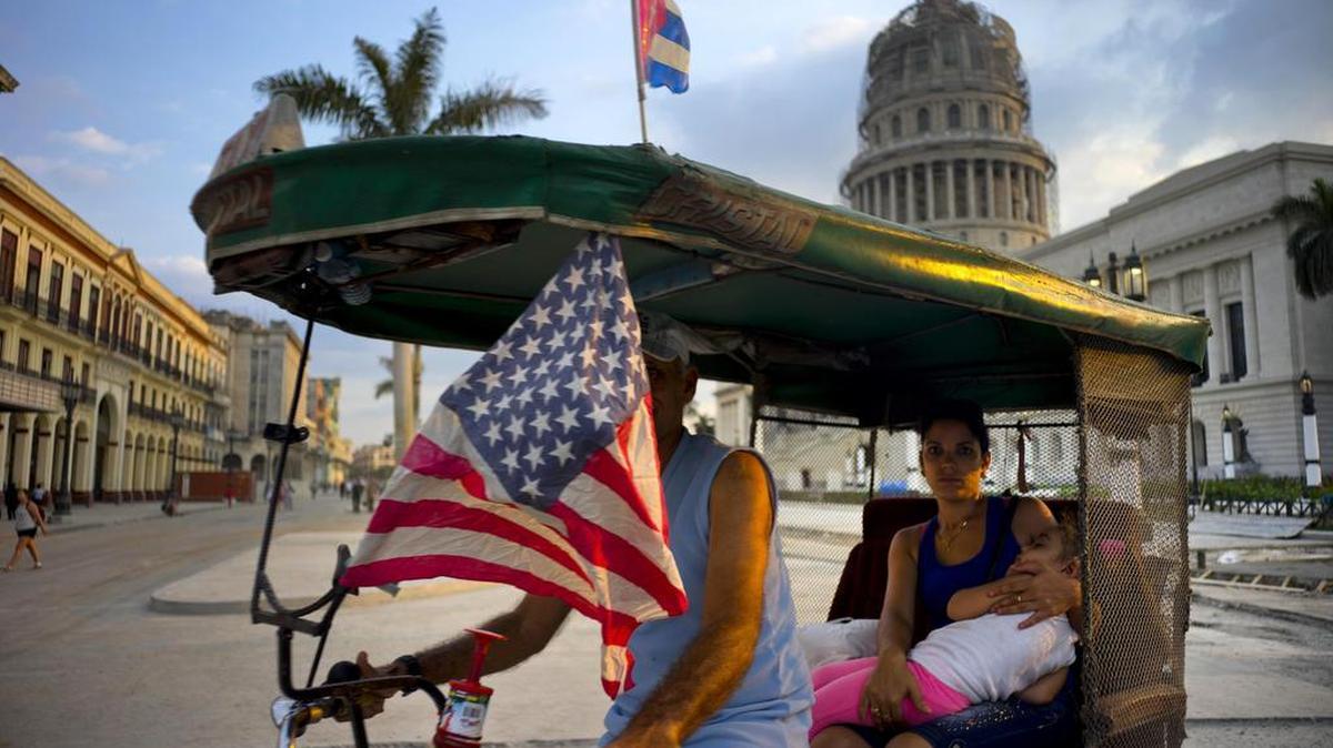 A bicycle taxi driver transports a woman and a sleeping girl near the Capitolio in Havana on Tuesday. His vehicle is adorned with both U.S. and Cuban flags leading up to President Obama’s visit.