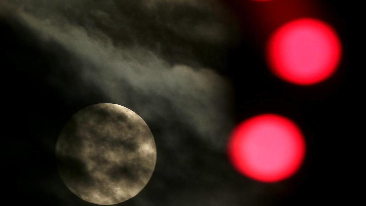 The nearly full-moon is seen among Christmas lights at a holiday display Dec. 24, 2015, in Lenexa, Kan.