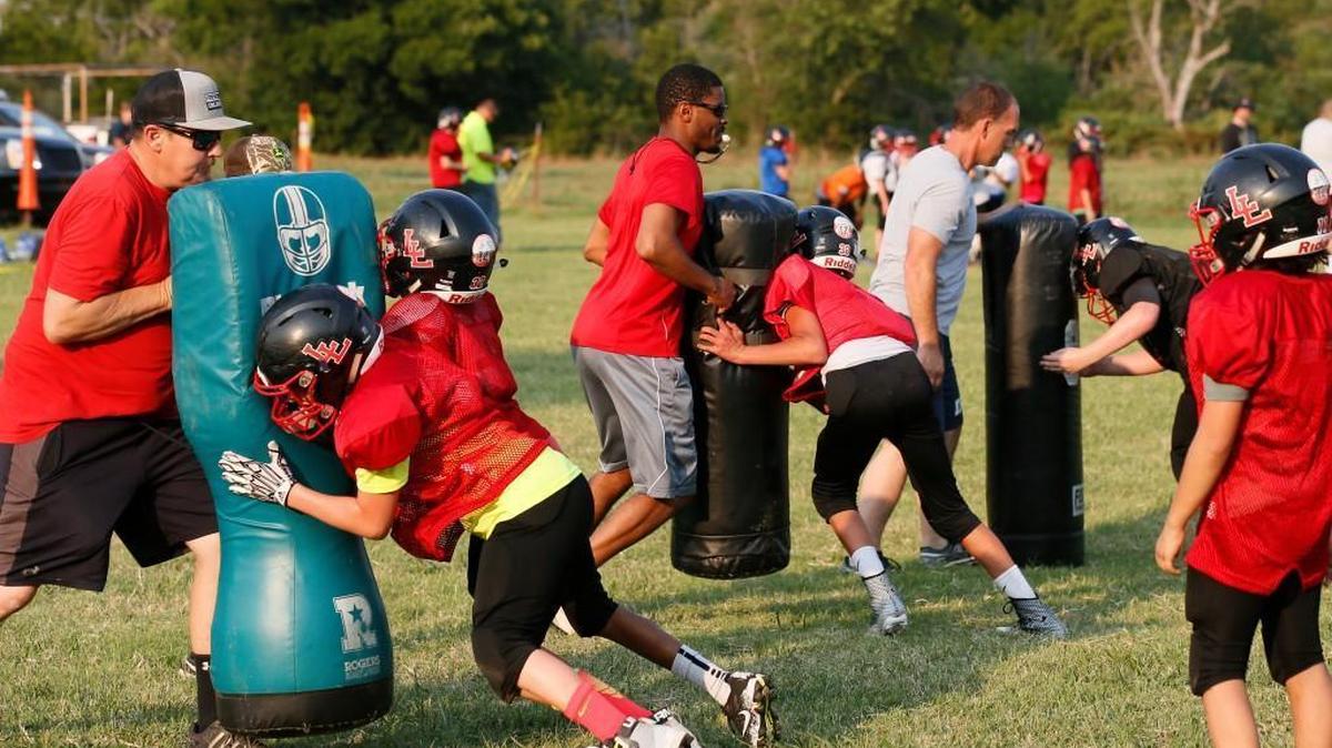 From left, volunteer coaches Pete Newsom, Antwan Richardson and Barry Garrett take the sixth grade team through drills during practice in Luther, Okla., Thursday, Aug. 3, 2017.