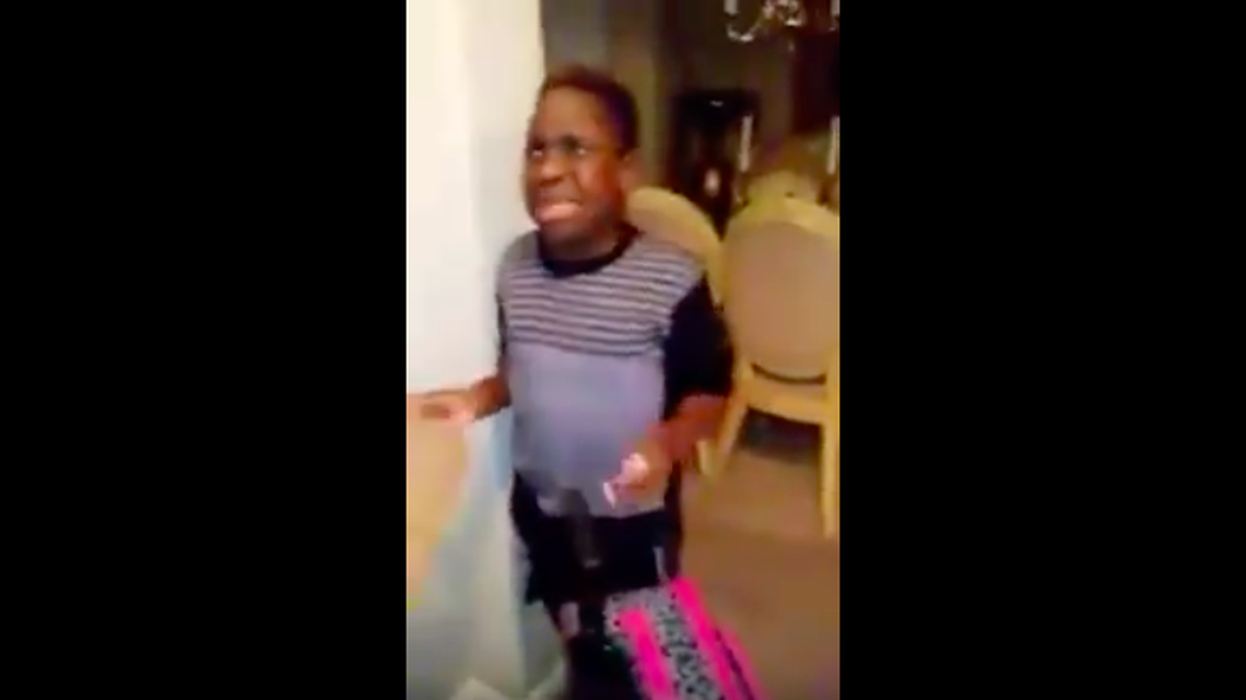 A screenshot from the video, as the mother forces her son to leave the house.
