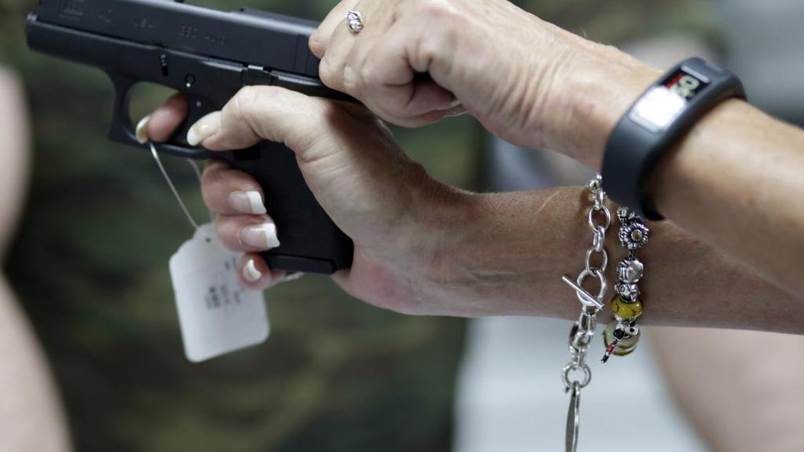 Sally Abrahamsen, of Pompano Beach, Fla., right, holds a Glock 42 pistol while shopping for a gun at the National Armory gun store and gun range, Tuesday, Jan. 5, 2016, in Pompano Beach, Fla. A new study by Harvard and Northeastern universities estimates that nearly half of the 265 million guns now owned privately belong to just 3 percent of Americans.