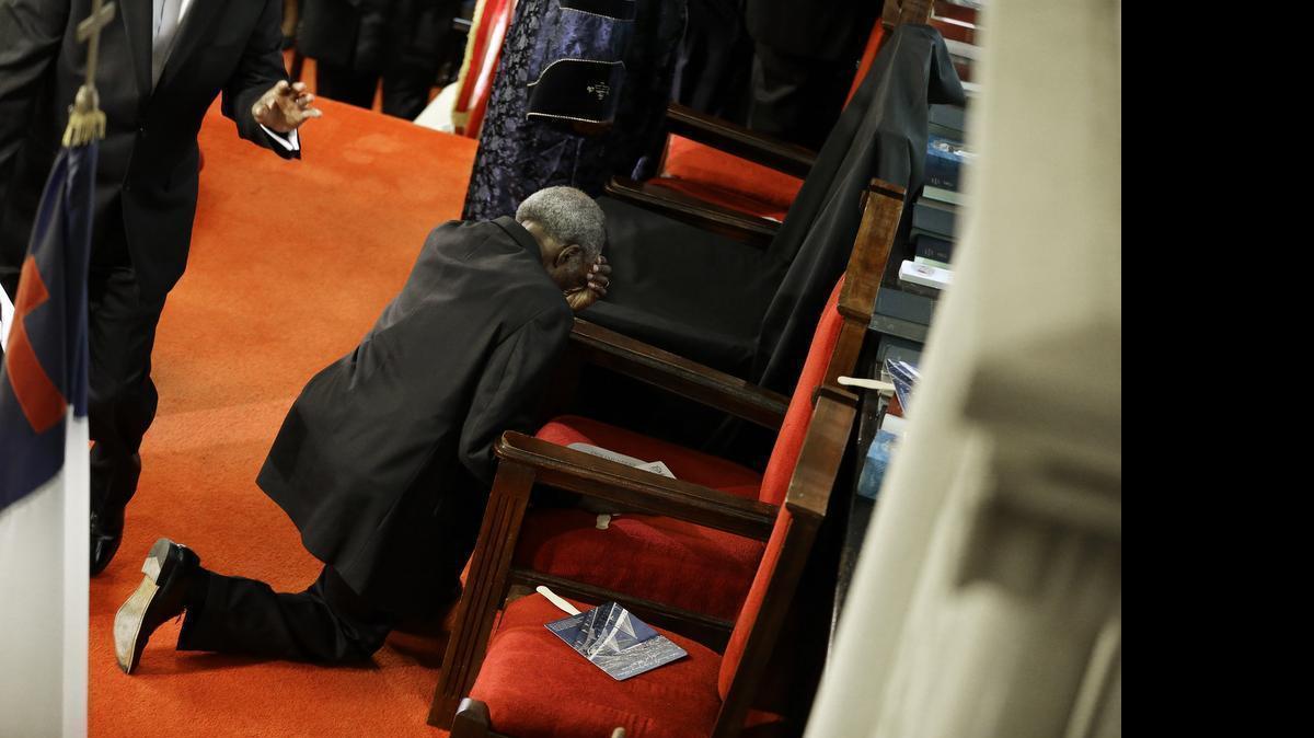 
A parishioner prays at the empty seat of the Rev. Clementa Pinckney at the Emanuel A.M.E. Church on Sunday, June 21, 2015, in Charleston, S.C., four days after a mass shooting claimed the lives of Pinckney and eight others.
