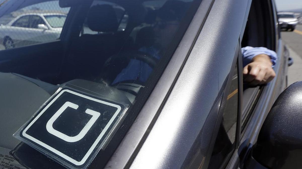 FILE - In this July 15, 2015, file photo, Uber driver Karim Amrani sits in his car parked near the San Francisco International Airport parking area.