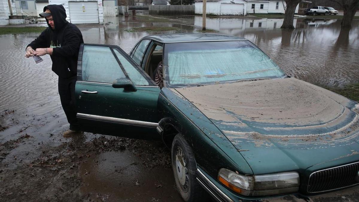 Thomas Barnard removes the registration from fiancee Jessica Klick’s 1995 Buick after floodwaters from the South Fork of the Sangamon River receded during a visit to the couple’s home in Kincaid, Ill., Thursday, Dec. 31, 2015. The car was almost completely submerged during the flooding.