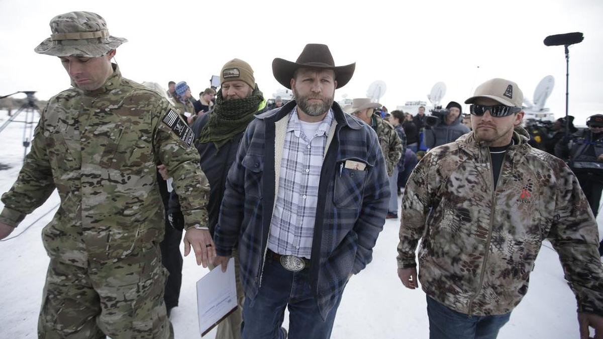 Ammon Bundy, center, one of the sons of Nevada rancher Cliven Bundy, walks off after speaking with reporters during a news conference at Malheur National Wildlife Refuge headquarters Monday near Burns, Ore. Bundy, who was involved in a 2014 standoff with the government over grazing rights told reporters on Monday that two local ranchers who face long prison sentences for setting fire to land have been treated unfairly.