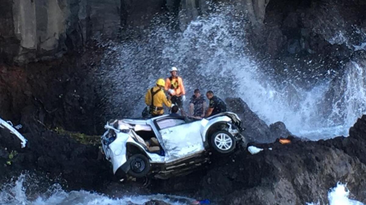 Rescue workers respond to the scene of a car crash off Maui’s Hana Highway in Hana, Hawaii. A Maui woman who was driving the vehicle when it plunged off the cliff is charged with murder in the death of her twin, who was in the passenger's seat. Prosecutors say Alexandria Duval, who is also known as Alison Dadow, intentionally caused the death of her sister, Anastasia Duval, also known as Ann Dadow. The 37-year-old sisters were traveling on Hana Highway when their Ford Explorer crashed into a rock wall last week. Police say the Explorer fell about 200 feet.
