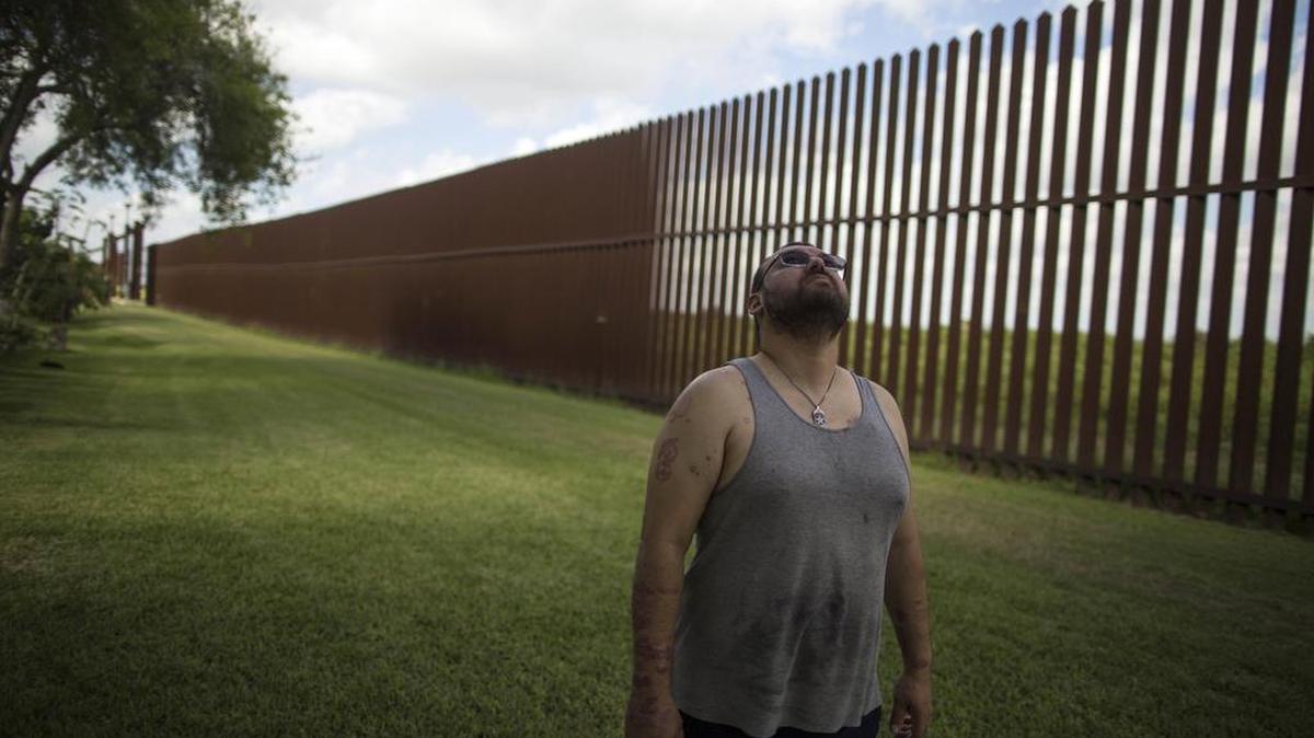 In this March 22, 2017, file photo, Antonio Reyes of Brownsville, Texas, stands by the U.S.-Mexico border fence near his home. Reyes said he’s seen people scale the border fence that bisects his backyard and jump down in seconds. Sometimes they carry bales of what appear to be drugs. A higher wall is “still not going to stop them,” he said. “They’ll shotput it or whatever they have to do.”