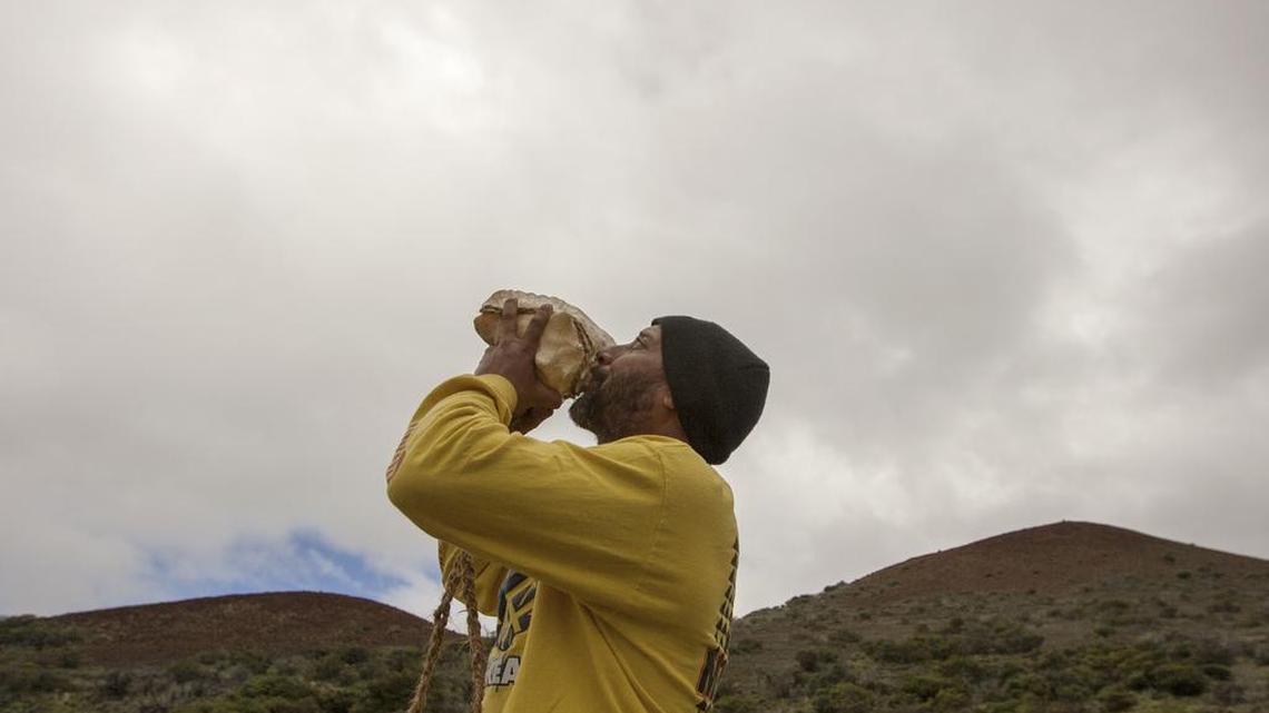 Kupono Mele-Ana-Kekua, of Kaaawa, Hawaii, blows a conch shell near the summit of Mauna Kea on Hawaii's Big Island in August. Mele-Ana-Kekua had been camping on the mountain in protest of the Thirty Meter Telescope. Construction equipment and vehicles that have sat idle since protesters blocked crews from building the giant telescope are being removed from a mountain that's considered sacred to some Native Hawaiians.