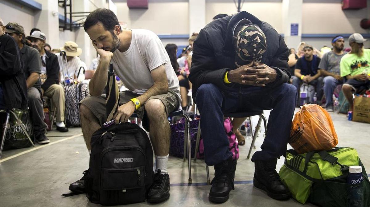 People rest while waiting to board a bus headed for San Antonio at an evacuation center in Corpus Christi, Texas on Friday, Aug. 25, 2017. (Nick Wagner/Austin American-Statesman via AP)