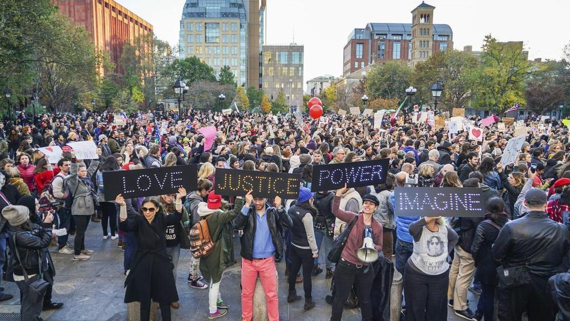 Four protestors hold signs as a large group takes part in a demonstration in opposition of Donald Trump's presidential election victory, Friday, Nov. 11, 2016, at Washington Square Park in New York. Dubbed a "love rally," the protesters marched from Washington Square Park uptown to Union Square.