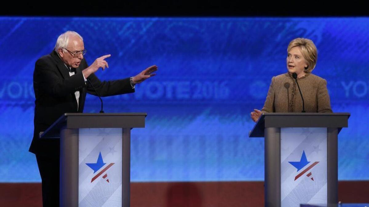 Bernie Sanders, left, and Hillary Clinton speak during an exchange during the Democratic presidential primary debate Saturday, Dec. 19, 2015, at Saint Anselm College in Manchester, N.H.