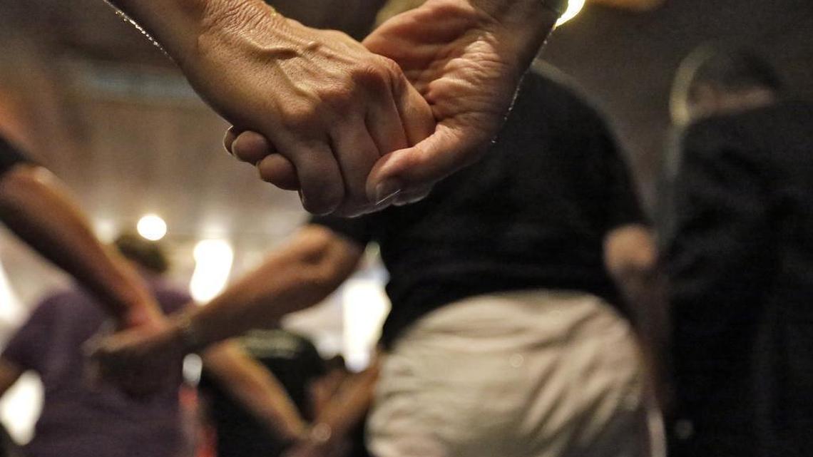 People at a pray vigil at the Joy Metropolitan Church hold hands after a fatal shooting at the Pulse Orlando nightclub Sunday in Orlando, Fla.